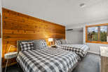 This inviting bedroom features two queen beds with stylish black and white checkered bedding, complemented by a warm wood-paneled wall.