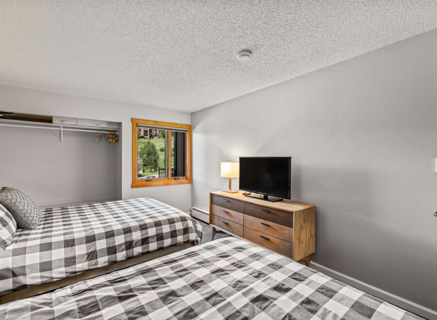 This inviting bedroom features two cozy beds with stylish gray and white checkered bedding, perfect for a vacation rental or family home.
