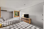 This inviting bedroom features two cozy beds with stylish gray and white checkered bedding, perfect for a vacation rental or family home.