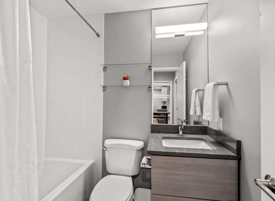 This modern bathroom features a clean and bright design with a combination of white tiled walls and neutral gray paint.