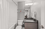 This modern bathroom features a clean and bright design with a combination of white tiled walls and neutral gray paint.