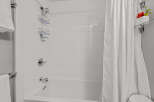 This bathroom showcases a pristine white tiled shower and tub combination, complemented by sleek chrome fixtures.