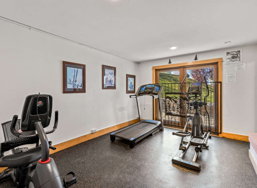 This home gym boasts a treadmill, elliptical machine, and stationary bike for convenient workouts.