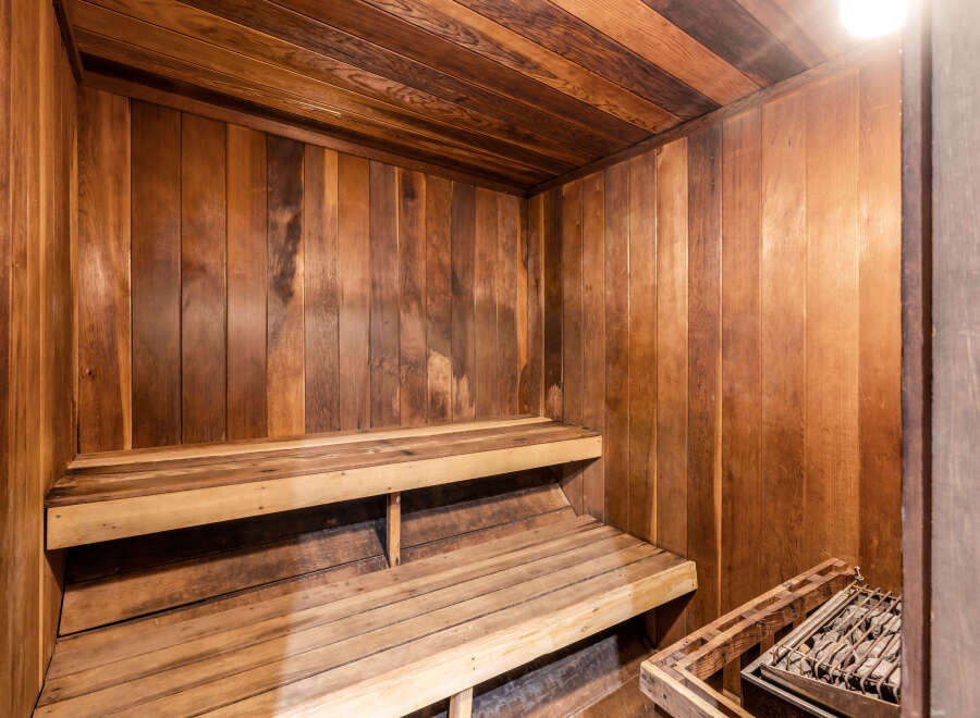 Indulge in the luxury of this home sauna, featuring beautiful wood paneling and comfortable tiered seating.