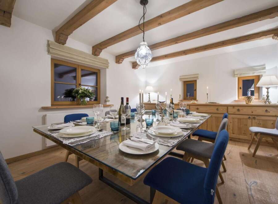 This dining room features a glass-top table set for a formal meal, complemented by elegant blue and grey chairs.