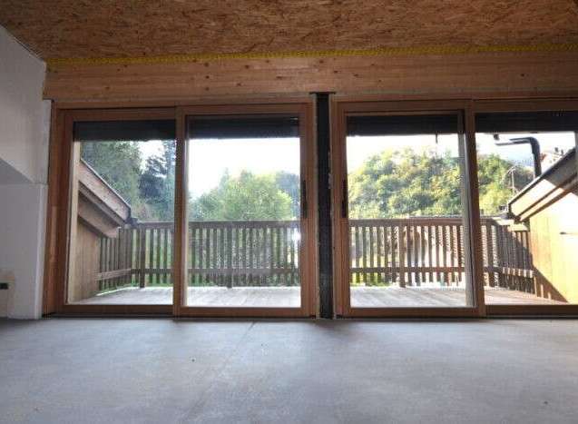 This property boasts large sliding glass doors that open onto a private wooden deck, offering stunning views of the surrounding nature.