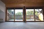 This property boasts large sliding glass doors that open onto a private wooden deck, offering stunning views of the surrounding nature.