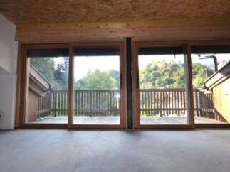This property boasts large sliding glass doors that open onto a private wooden deck, offering stunning views of the surrounding nature.