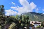 Nestled in a serene mountain landscape, this charming property boasts breathtaking views of lush forests and a clear blue sky dotted with clouds.