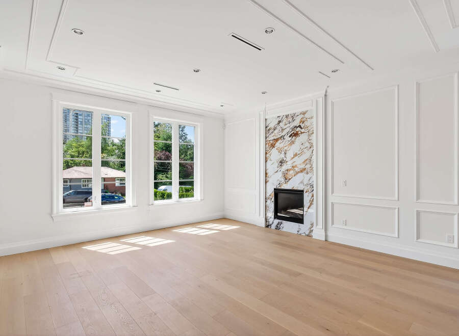 This bright, airy living room features pristine white walls, complemented by natural light streaming through large windows.
