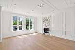 This bright, airy living room features pristine white walls, complemented by natural light streaming through large windows.