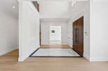 This grand foyer features a striking combination of materials, blending warm wood floors with a chic marble inlay.