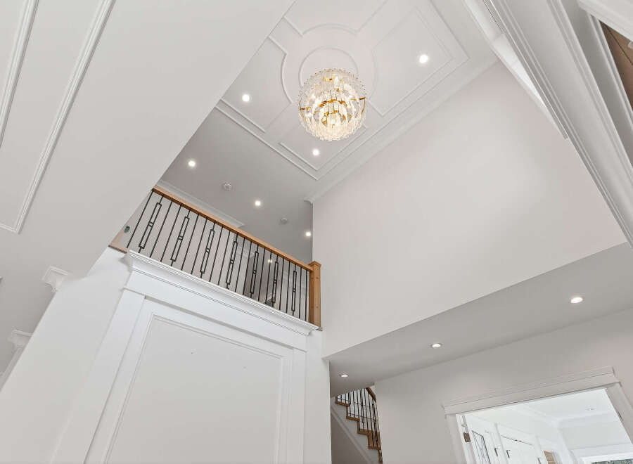 This grand foyer showcases soaring ceilings, intricate molding, and a stunning chandelier, creating an elegant and inviting entrance.