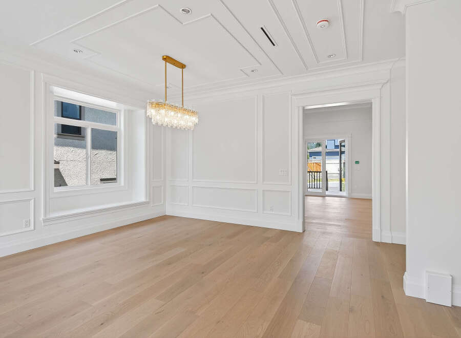 Step into this bright and airy room featuring exquisite millwork, a stunning crystal chandelier, and beautiful hardwood floors.