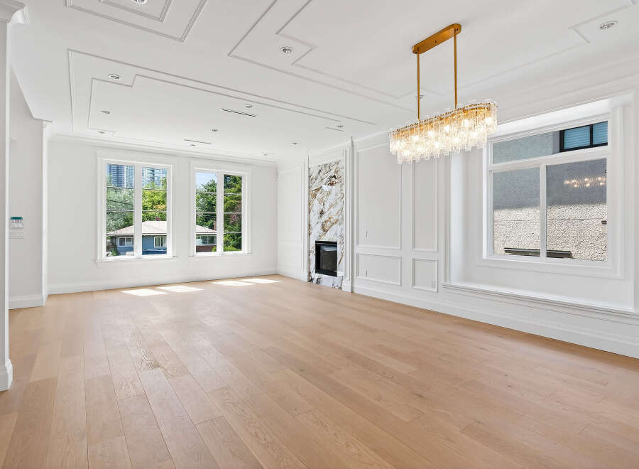 This stunning living room boasts exquisite architectural details, including ornate ceiling trim, custom wall paneling, and a stylish fireplace.