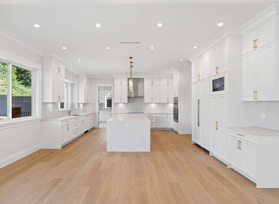 This spacious kitchen boasts a bright and airy design with its all-white cabinetry, countertops, and central island.