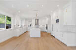 This spacious kitchen boasts a bright and airy design with its all-white cabinetry, countertops, and central island.