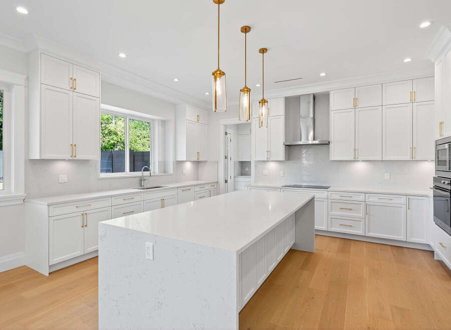 This stunning kitchen features shaker cabinets, a large island with a quartz countertop, and stainless steel appliances, perfect for cooking and entertaining.