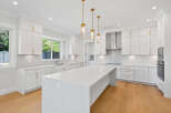 This stunning kitchen features shaker cabinets, a large island with a quartz countertop, and stainless steel appliances, perfect for cooking and entertaining.