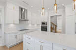 This is a modern kitchen featuring white cabinetry with gold hardware, stainless steel appliances, and a large center island.