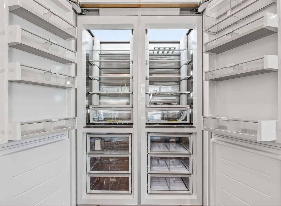 This is a modern, built-in refrigerator with a sleek white interior and stainless steel accents.