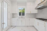 This modern kitchen features sleek, white cabinetry complemented by elegant gold hardware.