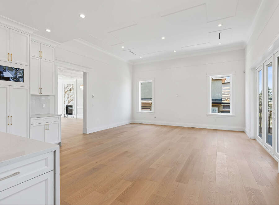 This spacious living area features beautiful hardwood floors, recessed lighting, and large windows that provide ample natural light.