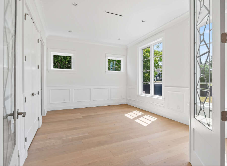 This is an elegant room with white walls, molding, and trim, complemented by light hardwood floors.