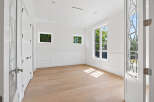 This is an elegant room with white walls, molding, and trim, complemented by light hardwood floors.
