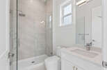 This bathroom features a modern design with a walk-in shower enclosed in clear glass, showcasing stylish gray tiling.