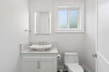 This immaculate, all-white powder room is a vision of modern elegance, featuring a vessel sink atop a stylish vanity.