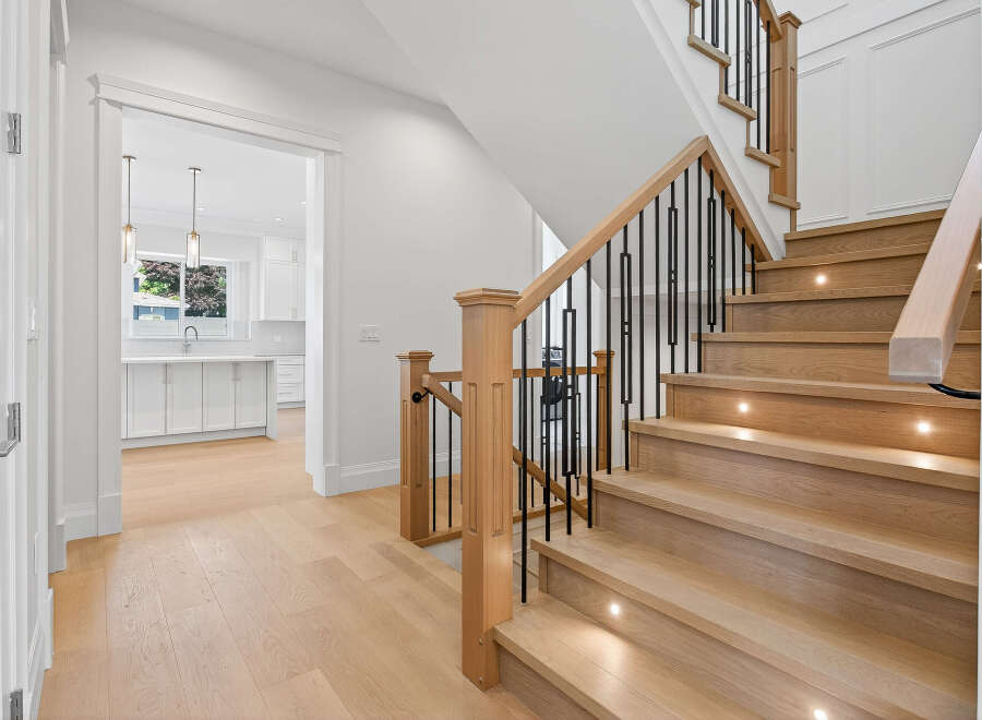 This inviting home features a stunning staircase with wood treads and black metal railings, illuminated by subtle step lights.