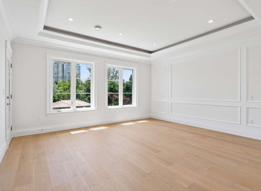 This elegant room features hardwood floors, two windows offering ample natural light, and sophisticated wall paneling.
