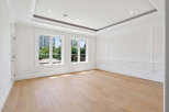 This elegant room features hardwood floors, two windows offering ample natural light, and sophisticated wall paneling.