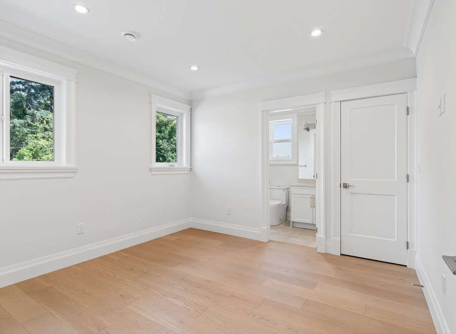 This is a bright and airy bedroom with hardwood floors and ample natural light from the windows.