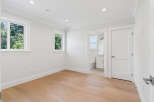 This is a bright and airy bedroom with hardwood floors and ample natural light from the windows.