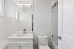 This is a well-lit, modern bathroom featuring a white vanity with a marble countertop, a sleek mirror with integrated lighting, and a toilet.