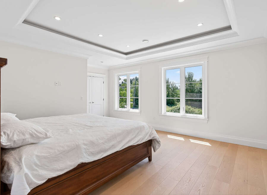 This bright and airy bedroom features hardwood floors, recessed lighting, and large windows that offer scenic views.