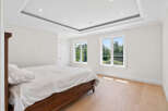 This bright and airy bedroom features hardwood floors, recessed lighting, and large windows that offer scenic views.