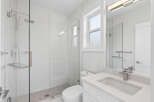 This modern bathroom features a sleek, frameless glass shower with a rainfall showerhead and convenient built-in shelf.