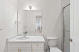 This bright bathroom features a white vanity with gold hardware, a sleek mirror, and a modern toilet.