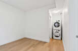 This bright and modern room features neutral walls, beautiful wood floors, and convenient in-unit laundry.