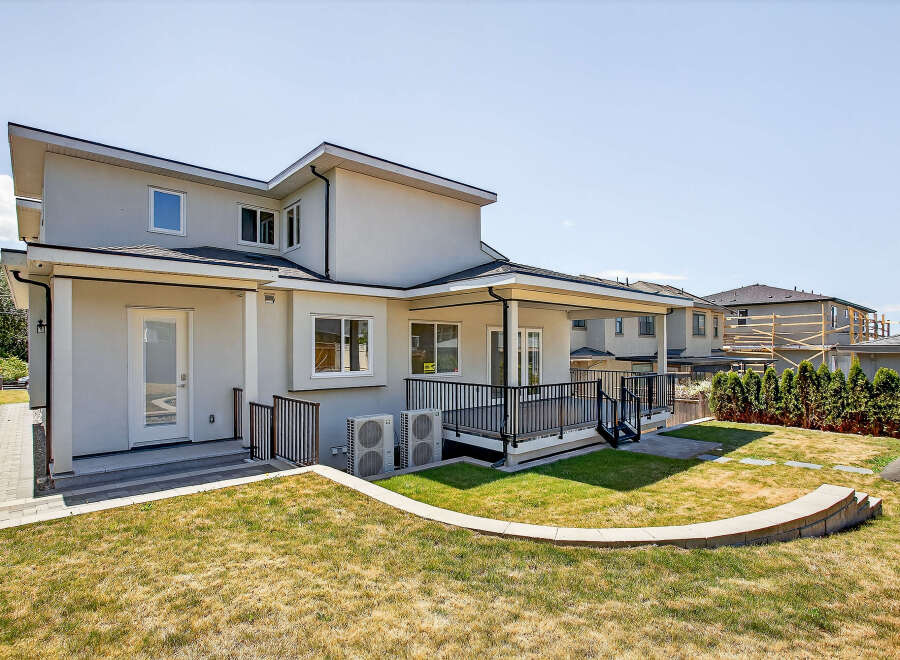 This property boasts a modern exterior with a well-maintained backyard, complete with a deck, patio, and lush lawn.