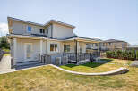 This property boasts a modern exterior with a well-maintained backyard, complete with a deck, patio, and lush lawn.
