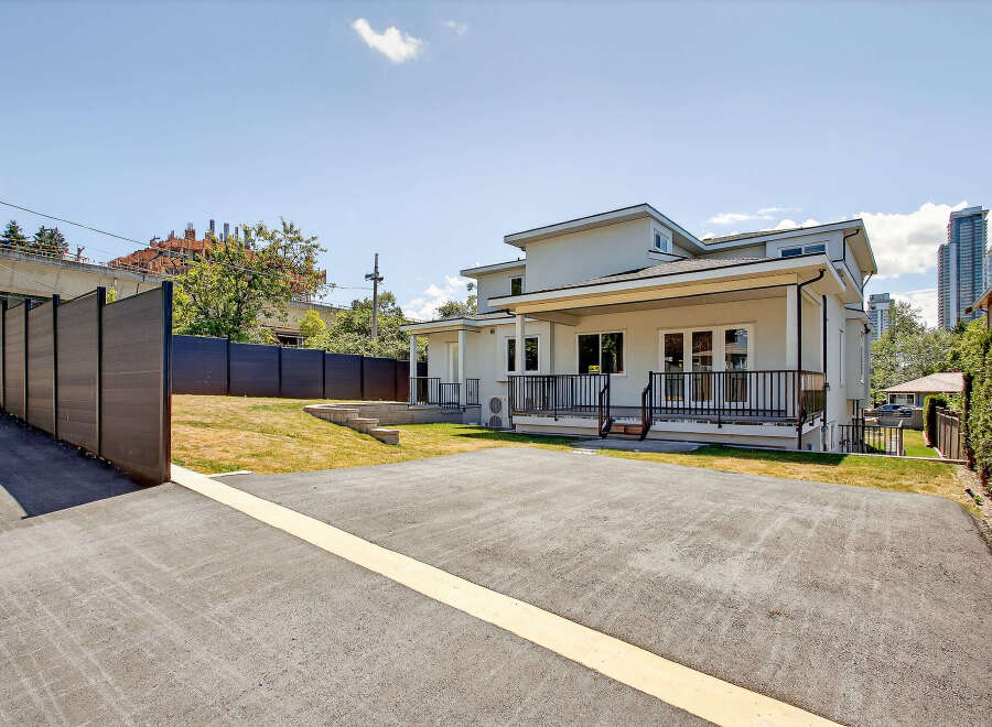 This modern home boasts a spacious asphalt driveway and a well-maintained lawn, perfect for outdoor activities.
