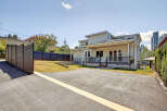 This modern home boasts a spacious asphalt driveway and a well-maintained lawn, perfect for outdoor activities.