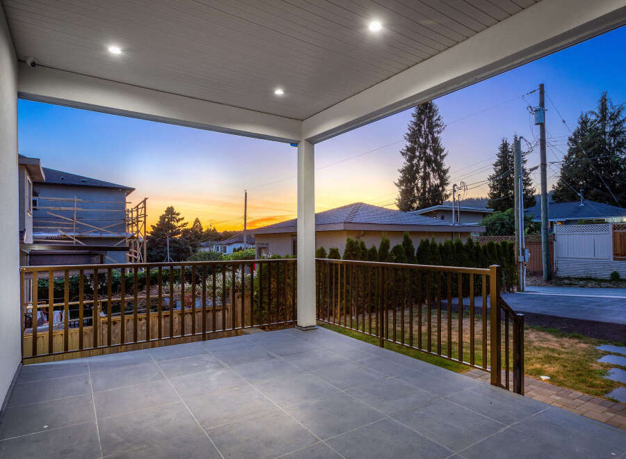 Enjoy outdoor living on this covered patio with sleek tile flooring and a stylish railing.