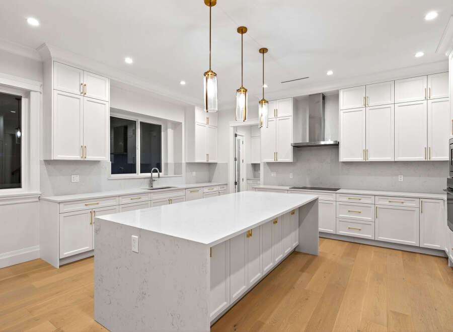 This stunning kitchen features bright white cabinetry complemented by elegant gold hardware and pendant lighting, creating a luxurious and inviting space.