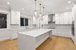 This stunning kitchen features bright white cabinetry complemented by elegant gold hardware and pendant lighting, creating a luxurious and inviting space.