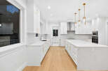 This bright, open-concept kitchen features all-white cabinetry accented with gold hardware, creating a luxurious and modern feel.